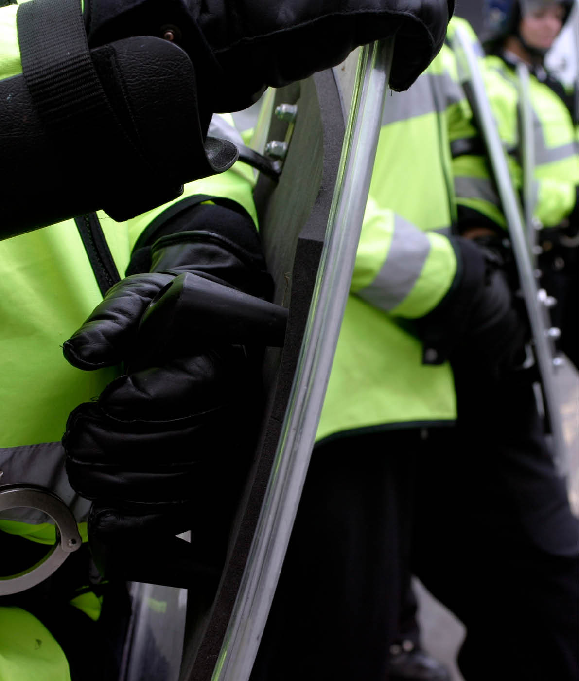 British police officers in riot gear form a human wall during a demonstration.